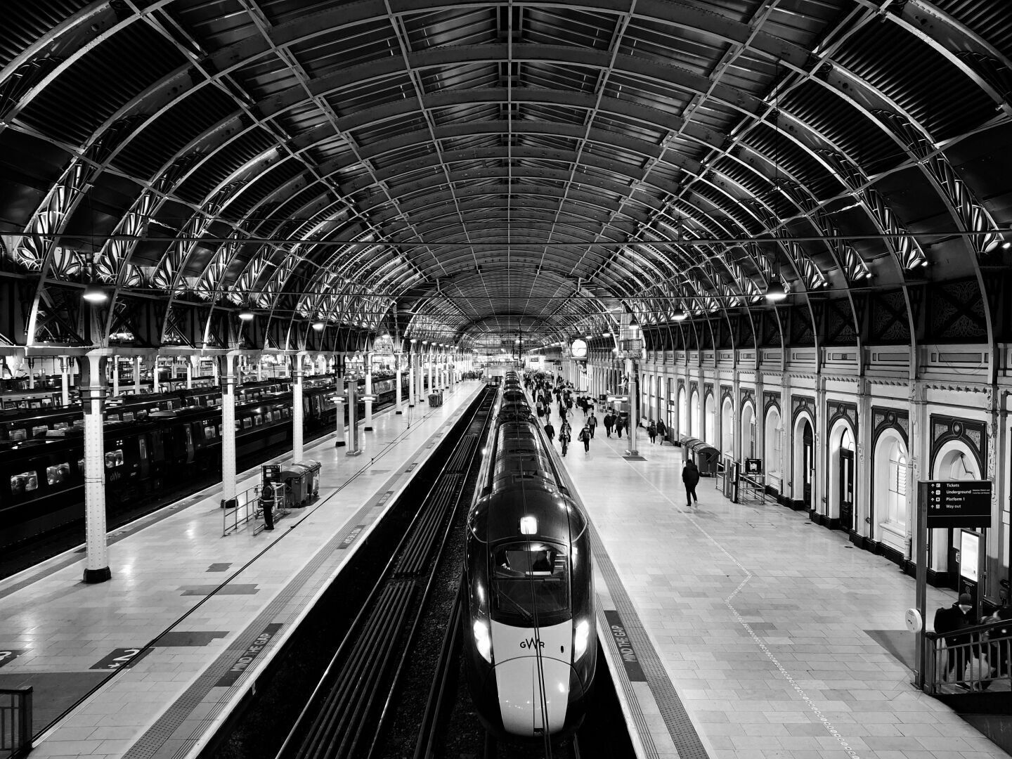 Inside a train station, a curved ceiling. The picture is grayscale