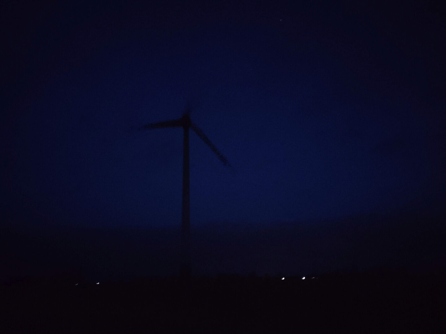 A rather poor photo - also a few years old. It shows a wind turbine from the ENERCON company in northern Germany, photographed at dusk and in the fog. It is quite blurry. The attraction lies in the shades of blue, the fog that permeates the image and the motion blur of the blades. 

Ein eher schlechtes Foto – auch schon einige Jahre alt.
Es zeigt eine in der Dämmerung und im Nebel fotografierte Windenergieanlage der Firma ENERCON in Norddeutschland. Es ist recht unscharf. Den Reiz machen die Blautöne, der Nebel, der das Bild durchzieht und die Bewegungsunschärfe der Flügel aus.