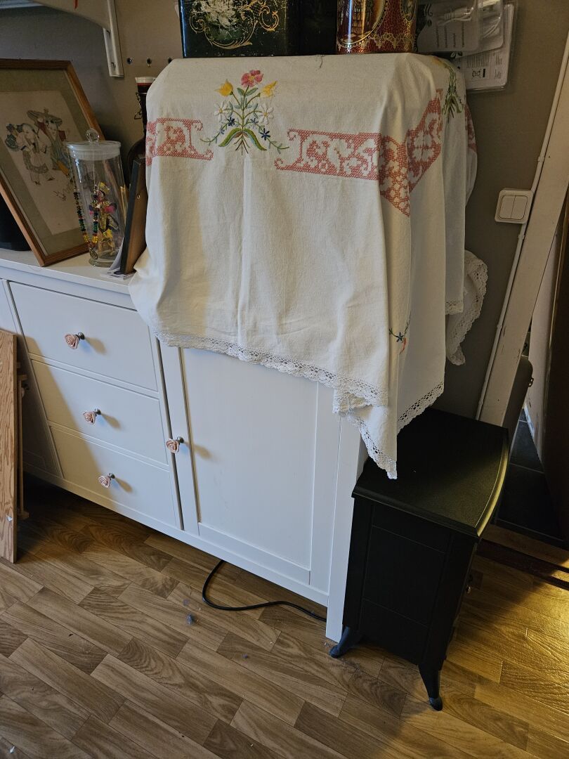 The chest and the fake iron stove. The chest is an IKEA unit where I've replaced the black knobs with pink roses. On top of the chest is a box like thingy covored with a white cloth embroidered with flowers.