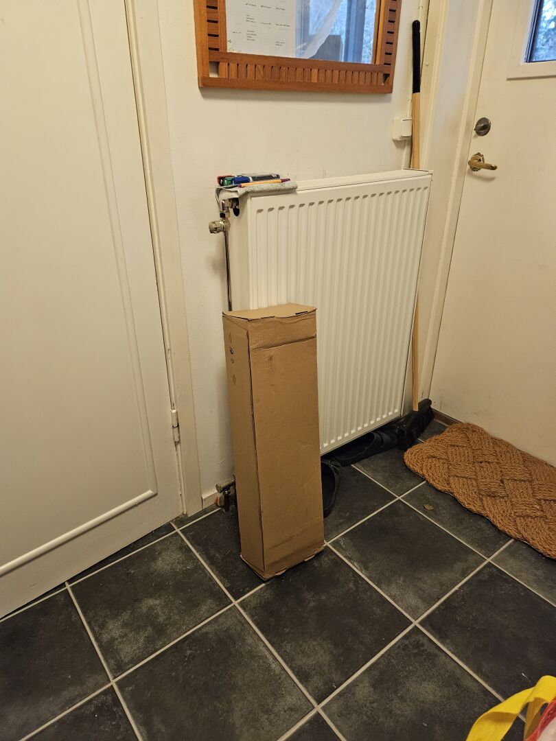 A short and heavy cardboard box leaning against the radiator in my foyer. It probably contains the motor to my adjustable desk.