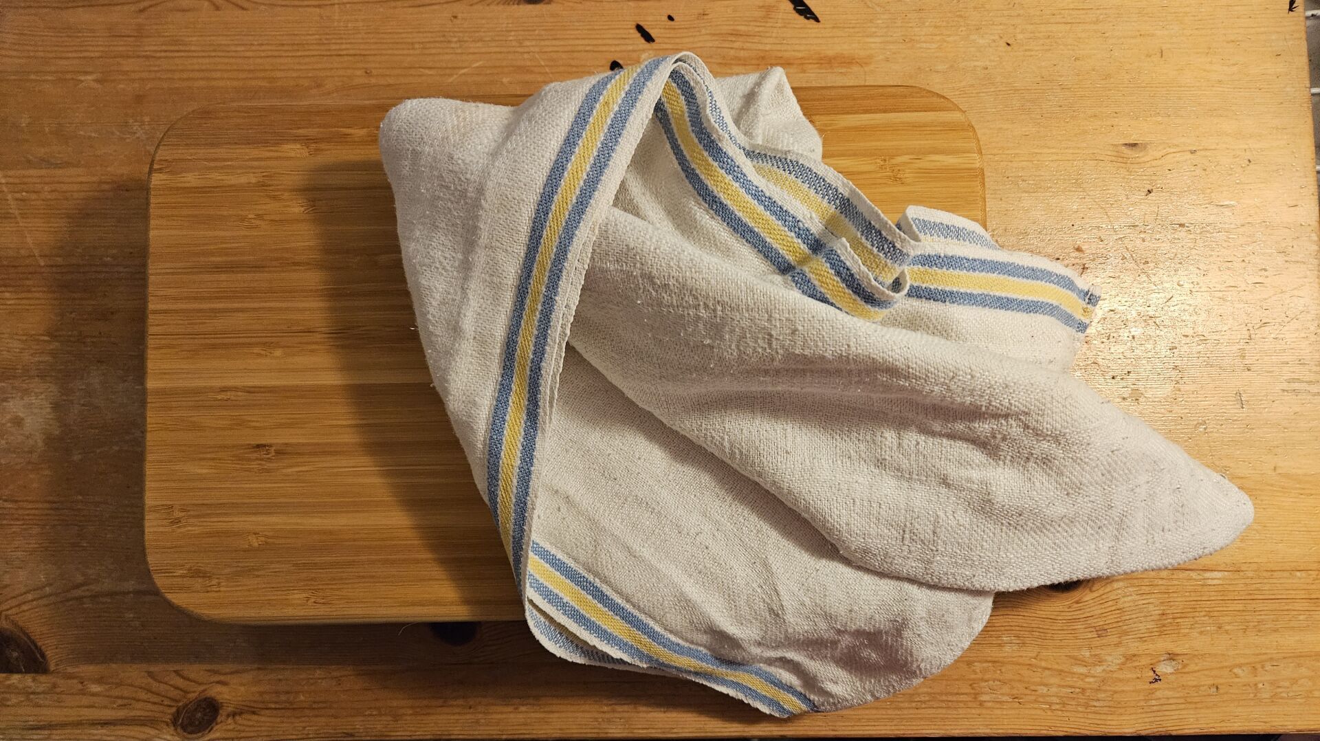 A cutting board with a linnen cloth on top.