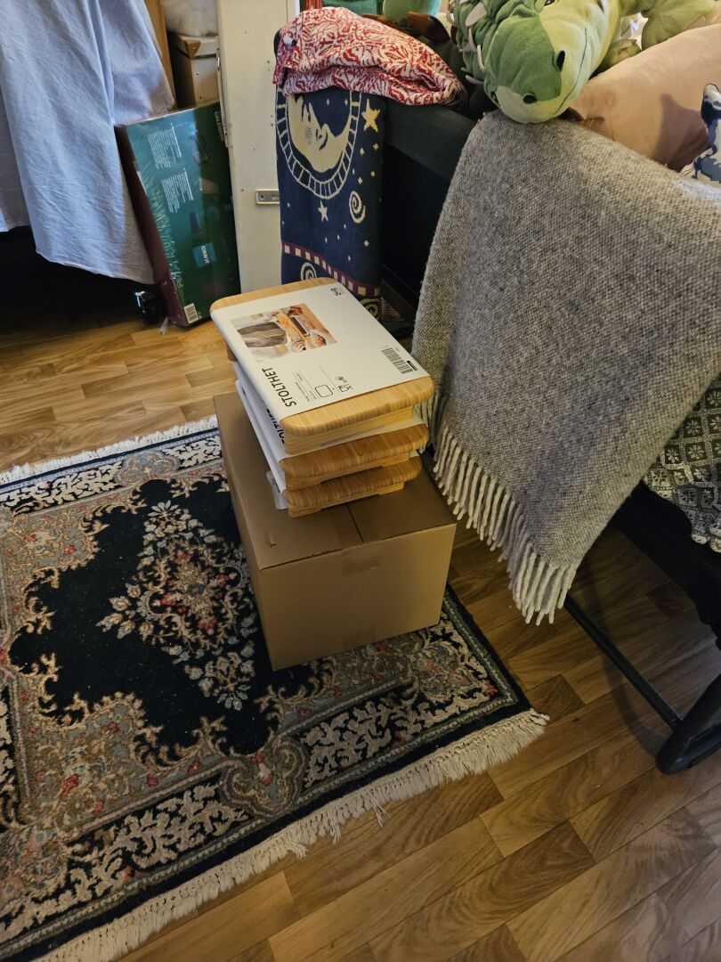 An almost cubic box with three bamboo boards with legs on top. I hope this box contains the rolling cart I need.