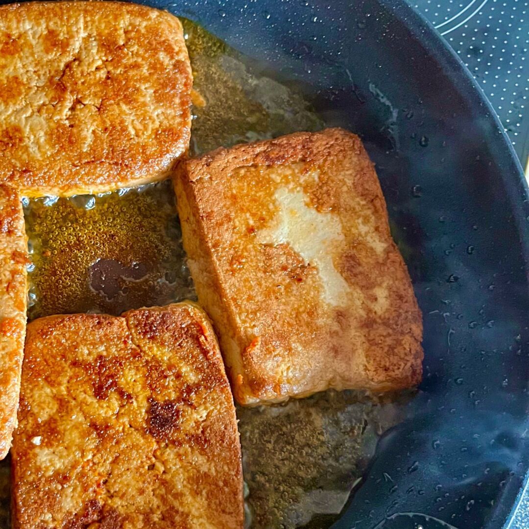 A piece of tofu in a pan that shows a cross