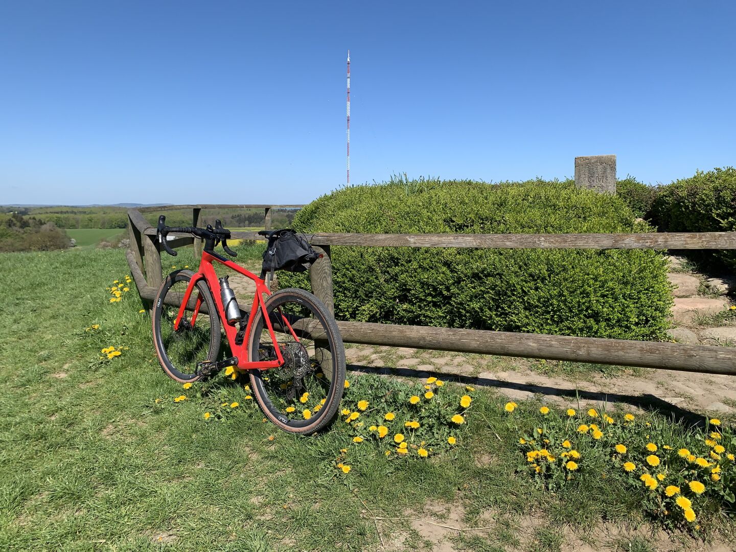 Bild eines roten Fahrrads vor der Gipfelmarkierung des Bungsbergs