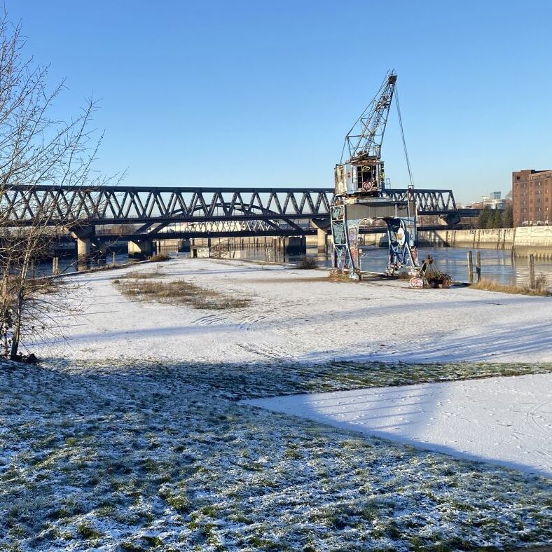 Alter Ladekran im winterlichen Billhafen. Im Hintergrund eine Eisenbahnbrücke.