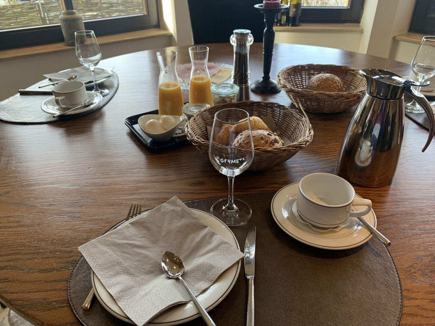 breakfast table with orange juice, coffee, bread, croissants, and more.
