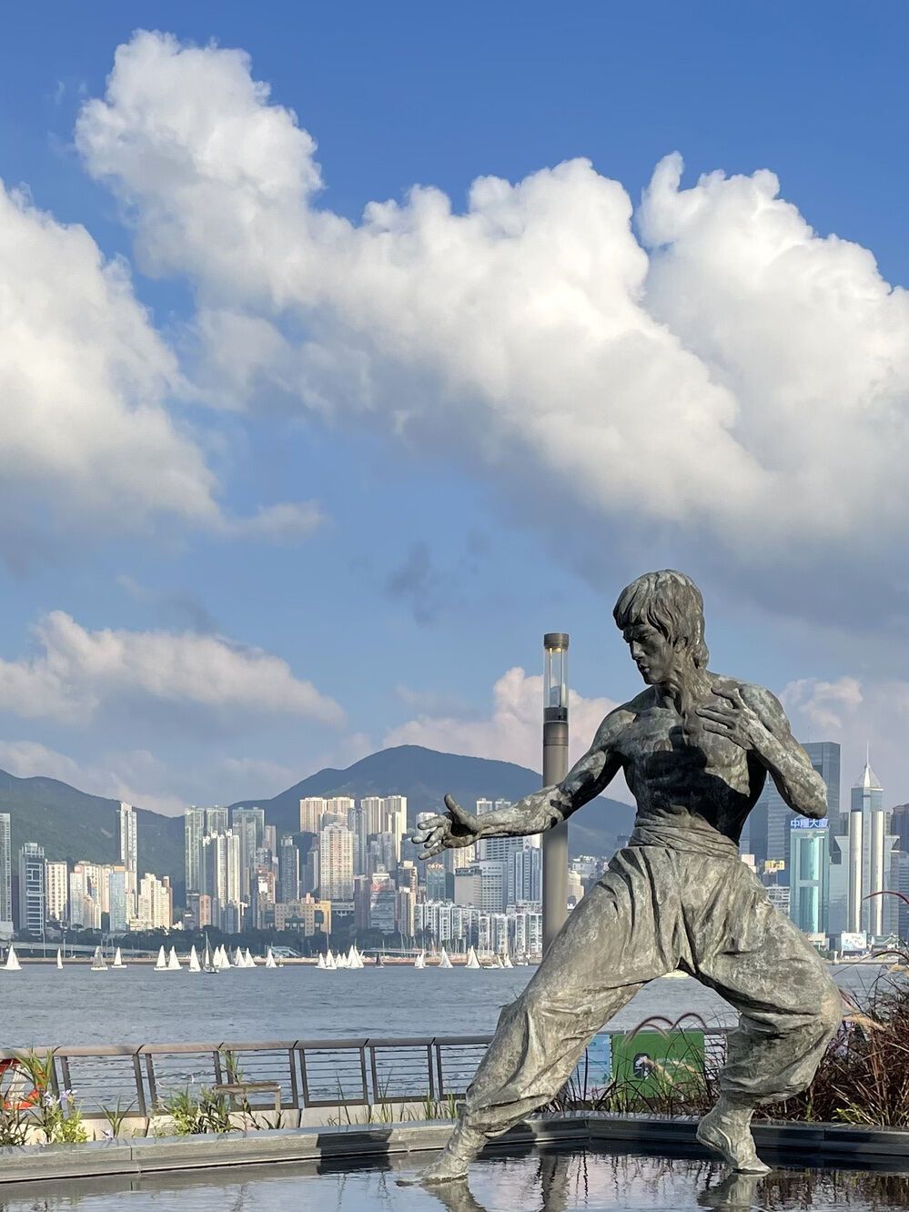 Statue of Bruce Lee overlooking Victoria Harbor and Hong Kong skyline in the background