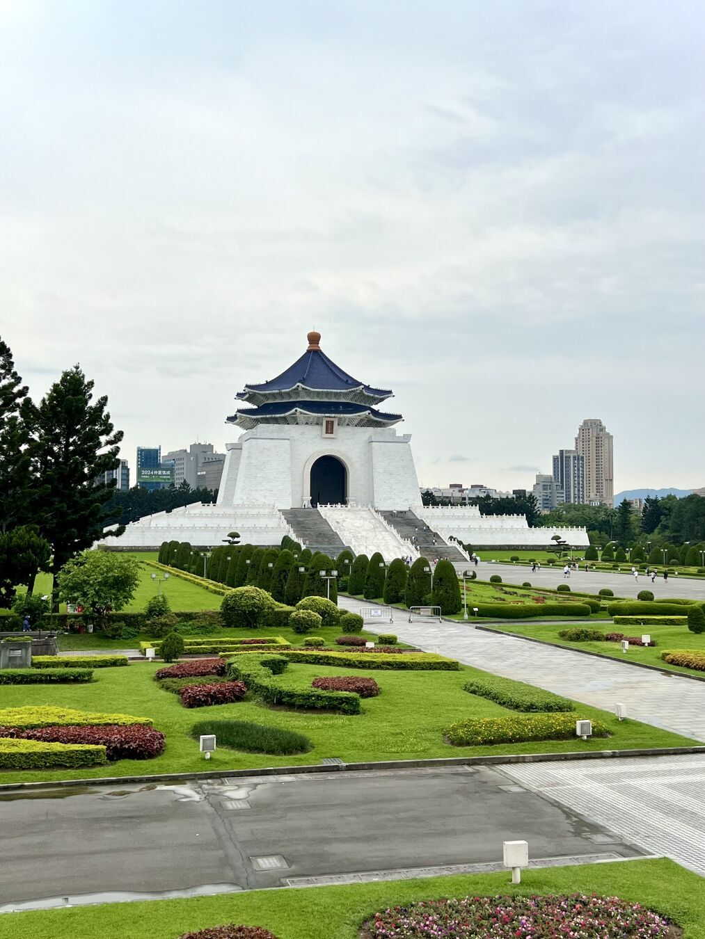 Ein Park, in der Bildmitte ein historisches asiatisches Gebäude. Der Himmel ist bewölkt.