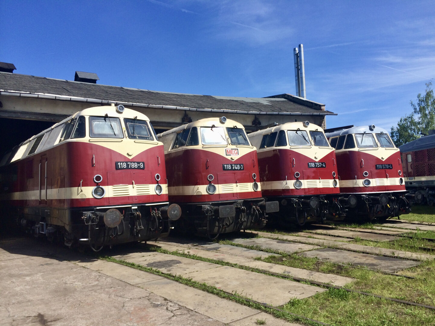 In einem Bw stehen vier Dieselloks der Baureihe V180 der DR nebeneinander.