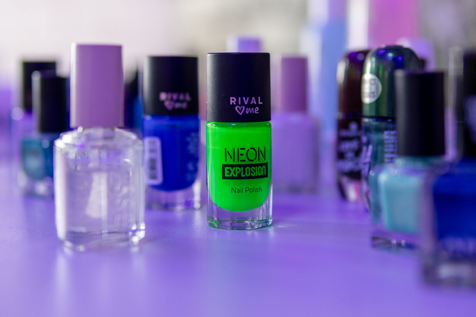 Verschiedene Flaschen Nagellack. Scharf abgebildet in der Mitte ist ein grüner Nagellack auf dem steht "NEON EXPLOSION"