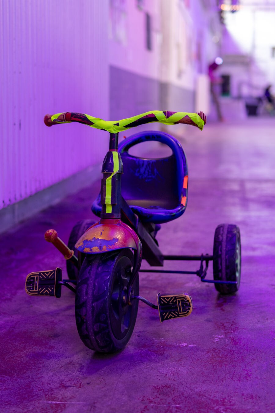 Ein kleine Dreirad steht in einem Flur. Der Rahmen ist mit Neontape beklebt.
