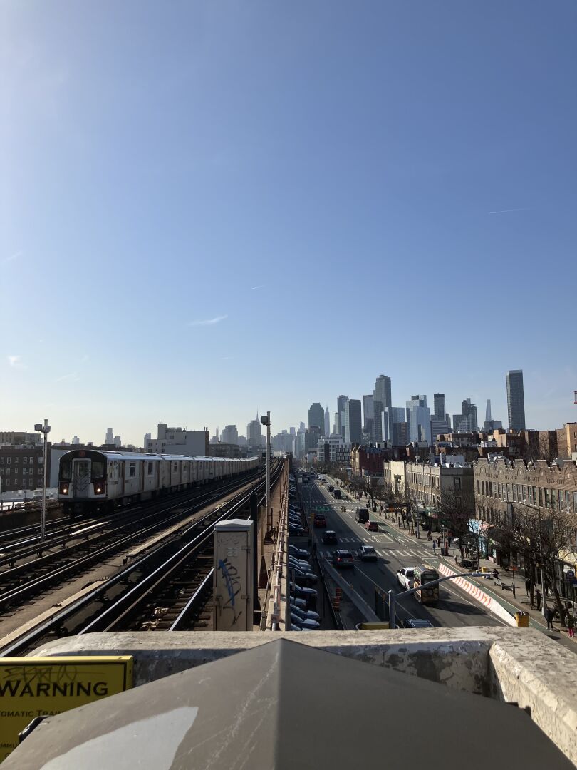 View of the NYC skyline from the platform of the 46th St station in Sunnyside. 7 train approaching from the opposite direction.
