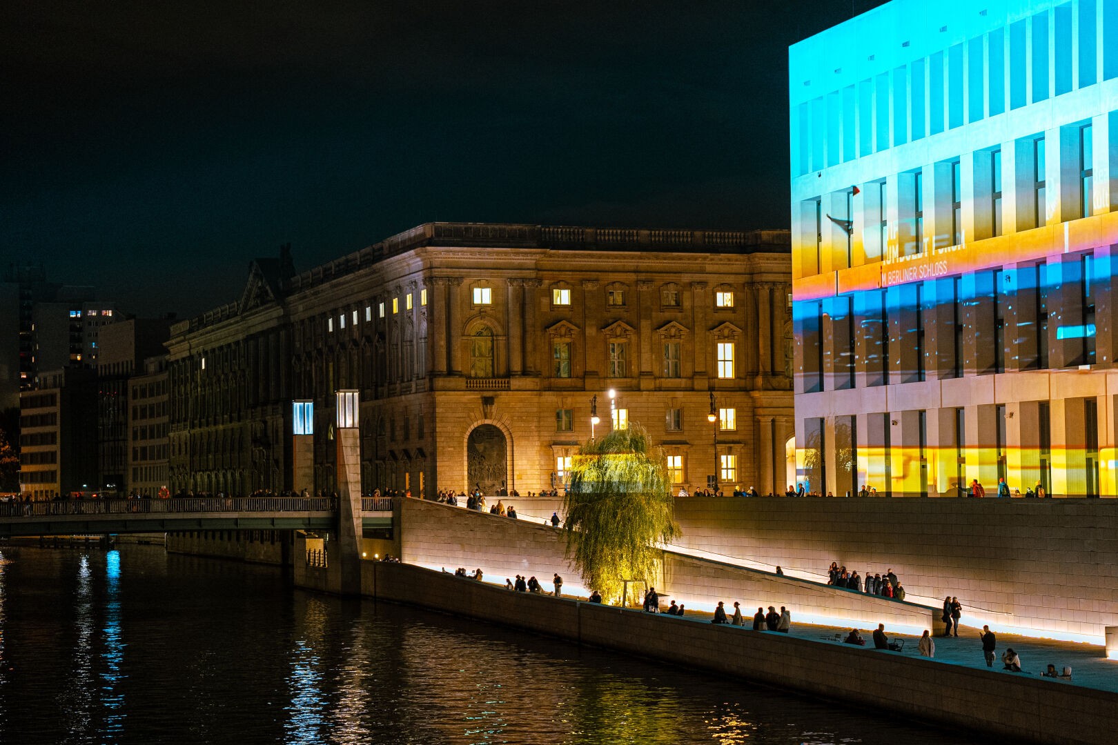 Museumsinsel (museum island) in Berlin at night during the festival of lights. Vibrant glowing buildings with the Spree in the center of the image.