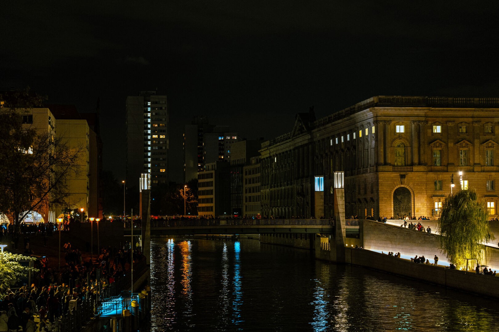 Similar to the first image: Museumsinsel Berlin at night during the festival of lights. Vibrant glowing buildings with the Spree in the center of the image.