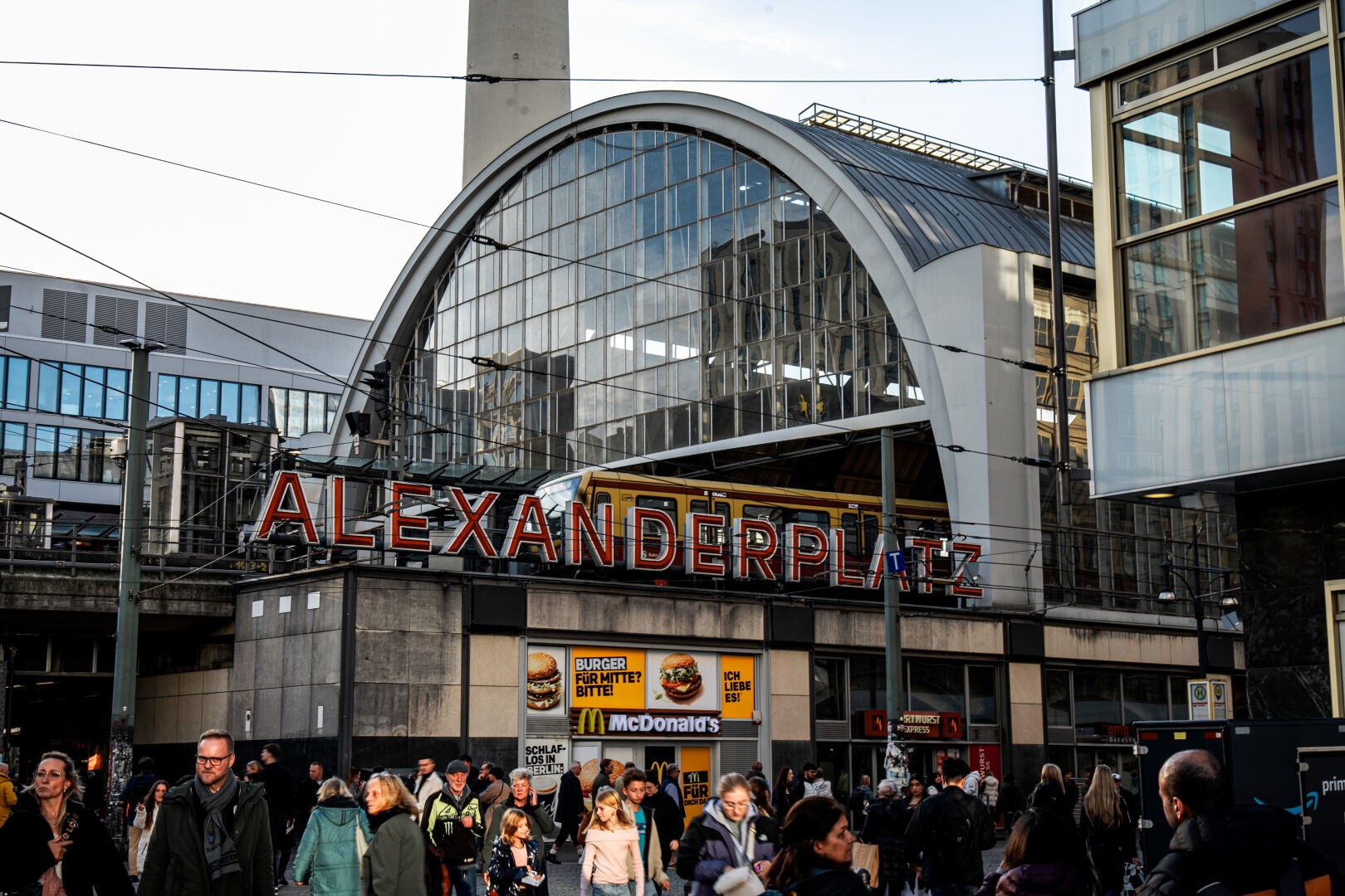 Public place in Berlin: The train station Alexanderplatz in the center. People in the foreground during golden hour.