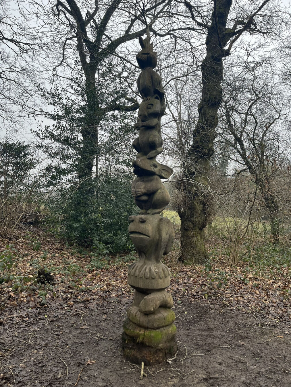 A wooden totem pole, comprised of carvings of different small animals.